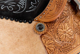 close up Wyoming flower tooling and brown iron conchos saddle